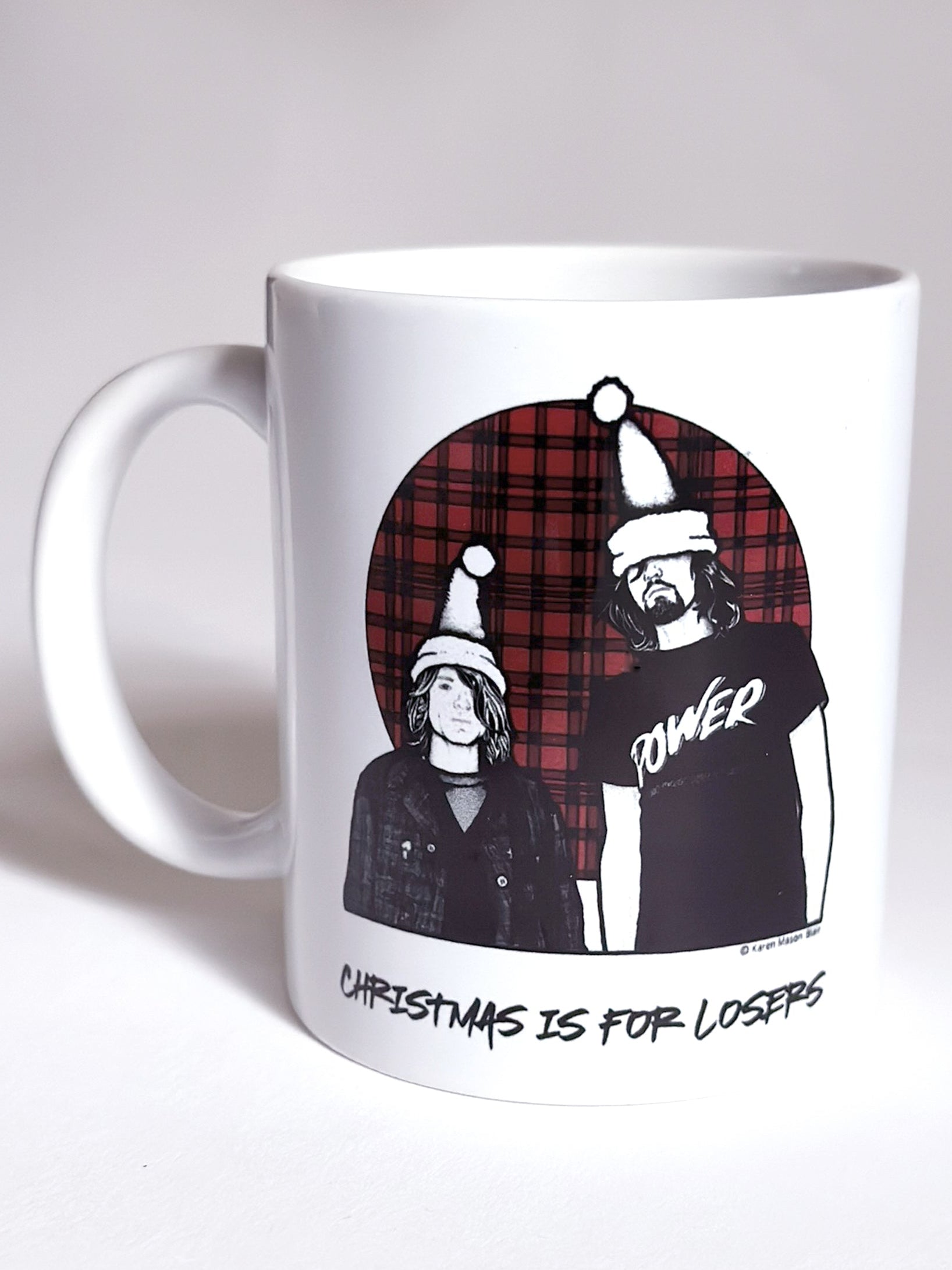 White coffee mug with graphic design of Nirvana wearing Christmas hats and text on a white